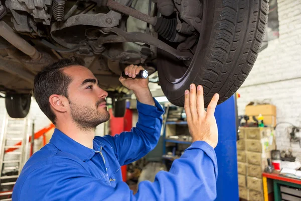 Joven mecánico atractivo trabajando en un coche en el garaje — Foto de Stock