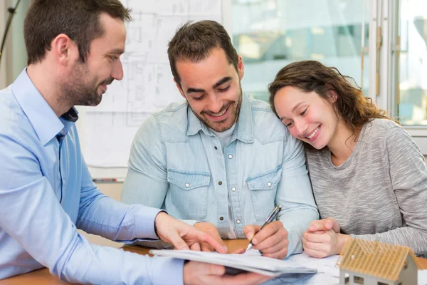 Jeunes gens attrayants signer cotract avec la réunion de l'immobilier — Photo