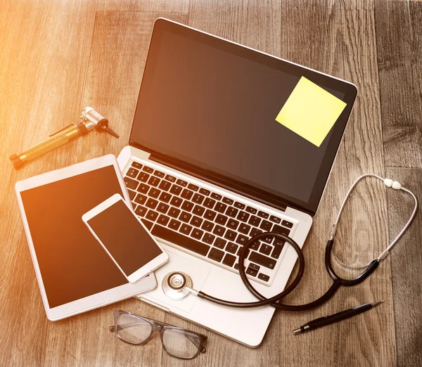 Dřevo stolu lékaře ve vysokém rozlišení s notebooku, tabletu a mo — Stock fotografie