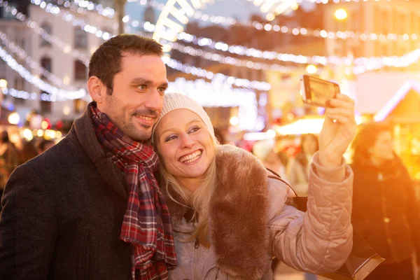 Jeune couple attrayant dans un marché de Noël prendre selfie — Photo