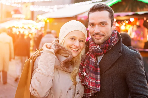 Young attractive couple in a christmas market — Stock Photo, Image