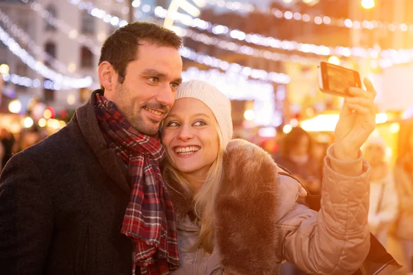 Jonge aantrekkelijke paar in een kerstmarkt nemen selfie — Stockfoto
