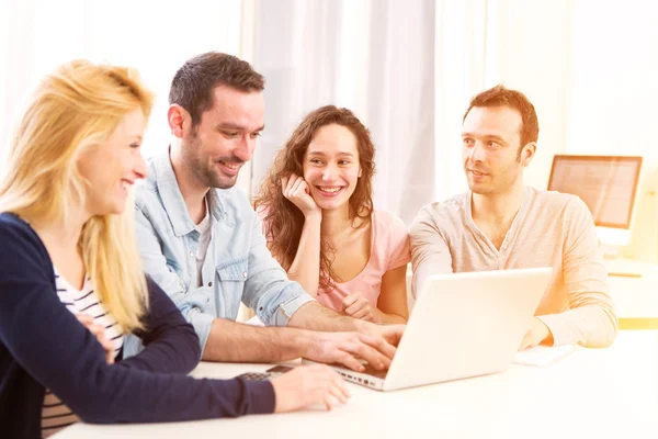 Gruppe von 4 jungen attraktiven Menschen, die an einem Laptop arbeiten — Stockfoto