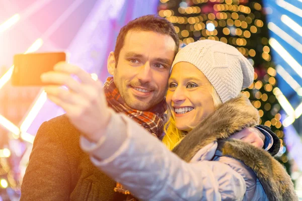 Joven pareja atractiva en un mercado de Navidad tomando selfie —  Fotos de Stock