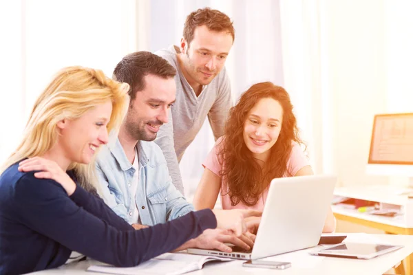 Gruppe von 4 jungen attraktiven Menschen, die an einem Laptop arbeiten — Stockfoto