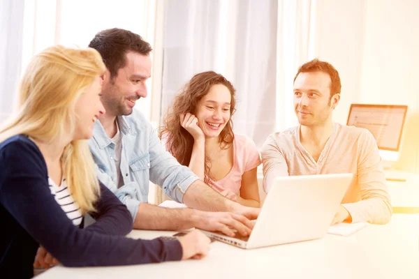 Gruppo di 4 giovani attraenti che lavorano su un computer portatile — Foto Stock