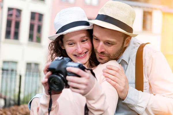 Jovem casal atraente verificando fotos na câmera — Fotografia de Stock