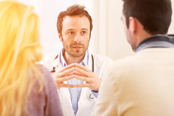 Young attractive doctor advising a young couple of patients — Stock Photo, Image