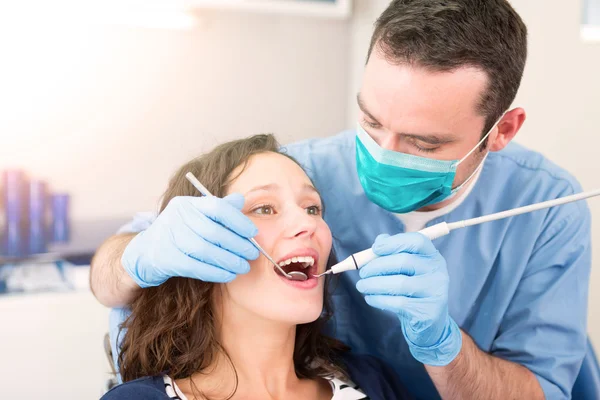 Joven mujer atractiva siendo curada por un dentista — Foto de Stock