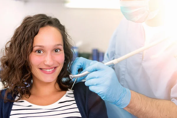 Joven mujer atractiva siendo curada por un dentista — Foto de Stock