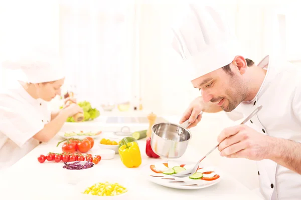 Giovane chef professionale attraente cucina nella sua cucina — Foto Stock