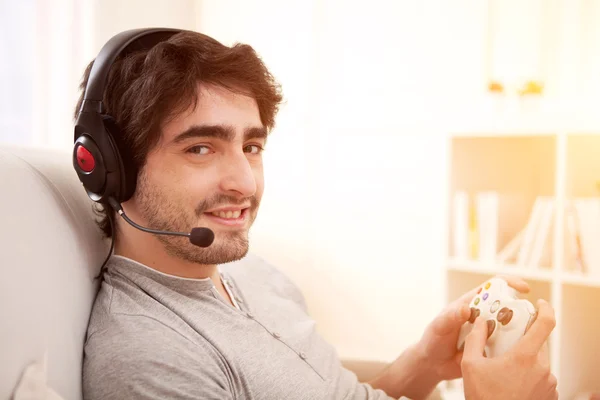 Jovem homem atraente jogando videogames em um sofá — Fotografia de Stock