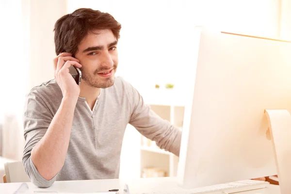 Genç gülümseyen adam bilgisayar önünde — Stok fotoğraf