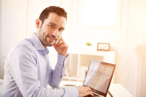 Jonge zakenman thuis werken op zijn laptop — Stockfoto