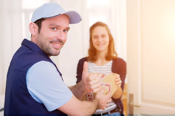 Delivery man handing over a parcel to customer — Stock Photo, Image