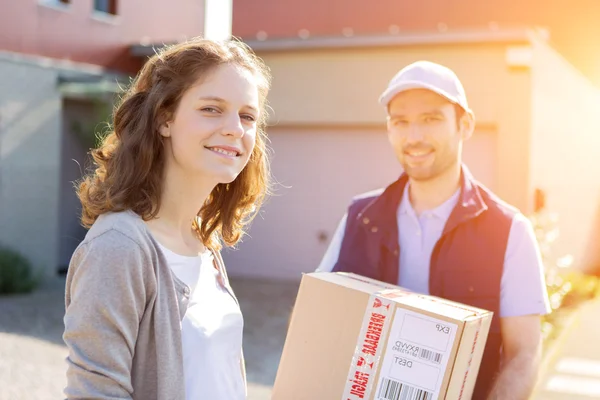Young attractive woman receiving parcel at home — Stock Photo, Image