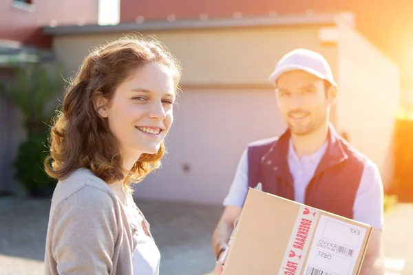 Young attractive woman receiving parcel at home — Stock Photo, Image