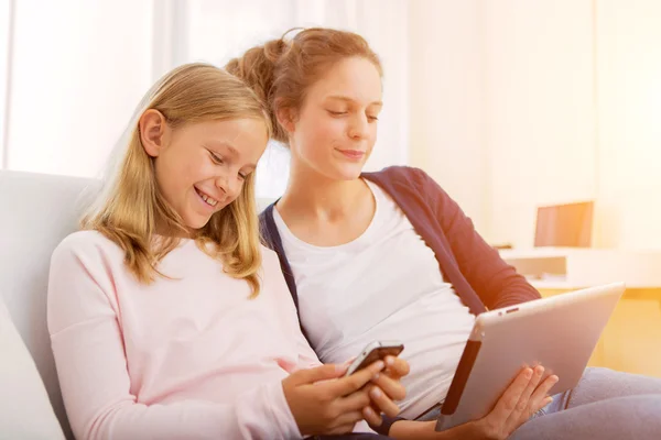 Mujer atractiva y hermana pequeña usando tableta — Foto de Stock