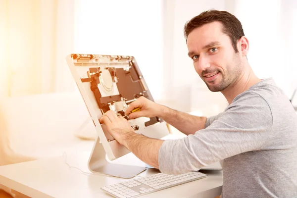 Молодой привлекательный мужчина ремонтирует компьютер — стоковое фото