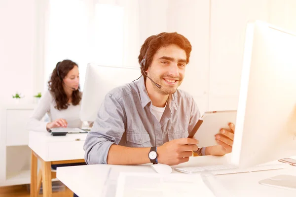 Junger attraktiver Mann, der in einem Callcenter arbeitet — Stockfoto