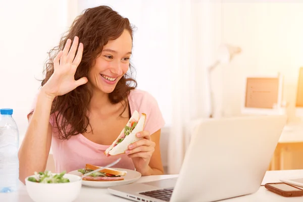 Ung attraktiv student äta medan du arbetar — Stockfoto