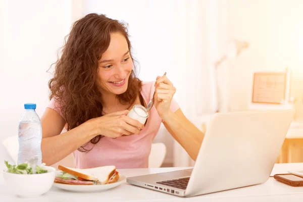 Giovane studente attraente mangiare mentre si lavora — Foto Stock