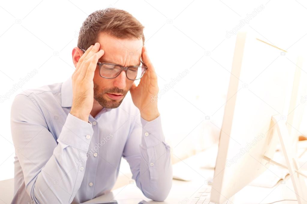 Young attractive man got a headache at the office