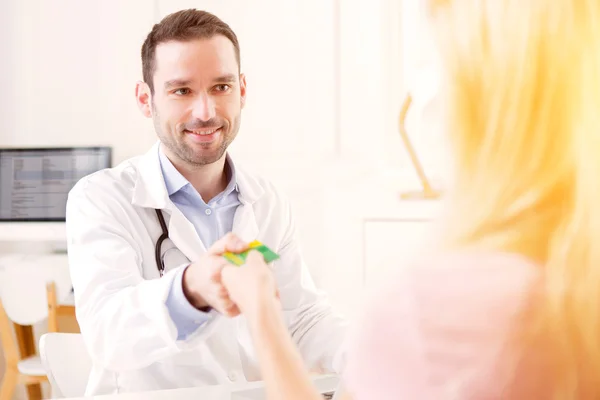 Joven médico atractivo escuchando a su paciente —  Fotos de Stock