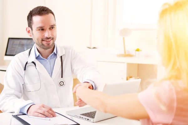 Joven médico atractivo escuchando a su paciente —  Fotos de Stock