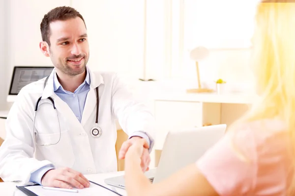 Joven médico atractivo escuchando a su paciente —  Fotos de Stock