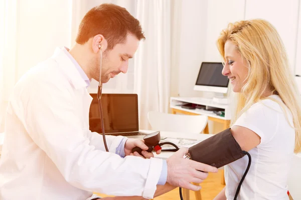 매력적인 젊은 의사 검사 환자의 혈압 — 스톡 사진
