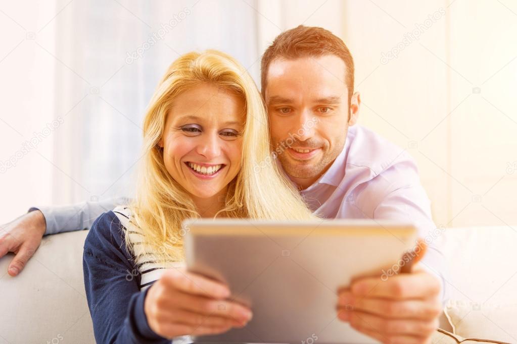 Young attractive couple having fun using tablet