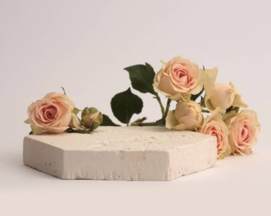 Stones platformu podyumu, gri arka planda bej kremalı gül çiçeği buketi. Ürün sunum sahnesi için en az boş temel.