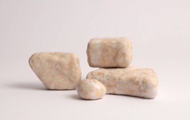 Gri nötr arka planda bej bej beyaz, altın taşlar platformu. En az boş ürün sunum sahnesi.