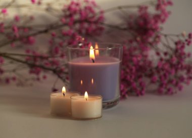 Yumuşak odaklanma. Duman bulanık yanan mumlar ve çiçek dalı. İyi akşamlar, gece lambası ve gölge bej arka plan. Minimalist hareketsiz hayat.