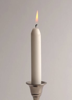 Gümüş şamdanda tek başına mum yakmak. İyi akşamlar, gece aydınlığı ve gölge grisi tarafsız arka plan. Minimalist hareketsiz hayat.