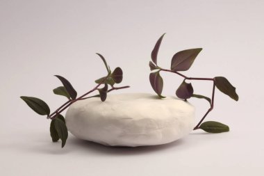 White Stones platform podyumu, bej gri doğal arka planda yaprak filizi. En az boş ürün sunum sahnesi.