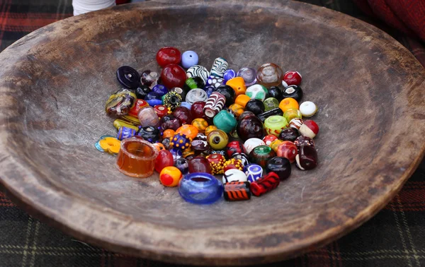 Diverse perline di vetro colorato su piastra di legno vintage Fotografia Stock