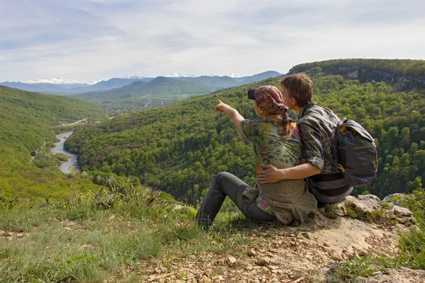 Çift kenarında oturur ve dağlara, kız Puan görünüyor — Stok fotoğraf