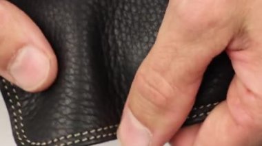 İnsan parmakları beyaz dikişli siyah doğal deri kalitesini kontrol eder, dış kısmı, sırt çantası veya çantanın bir kısmı, ürünün kalite kontrolü, yakın çekim