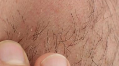 Adam parmaklarını kıllı yanağında gezdirir, tenine dokunur, sakal tıraşı olur, hijyen ve yüz bakımı ister, yakın çekim makrosu.