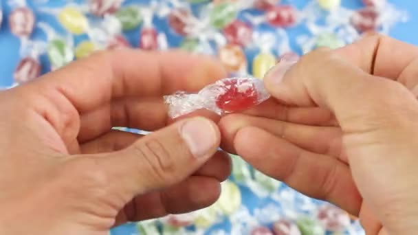 Las Manos Despliegan Una Piruleta Caramelo Rojo Una Envoltura Transparente — Vídeos de Stock