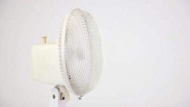 Beyaz arka planda solda dönen beyaz vantilatör, elektrik kliması ve yaz serinlemesi, yakın çekim ön görüş