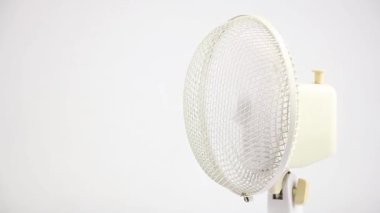 Beyaz arka planda sağ tarafta dönen beyaz vintage vantilatör, taşınabilir elektrikli klima ve soğutma, yakın çekim ön görüş