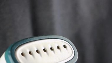 Buharlı buharlı giysiler için taşınabilir buharlı vapurun yakın plan görüntüsü, arka planda siyah kumaş