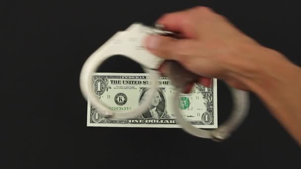 Hand Legt Handschellen Auf Einen Ein Dollar Schein Auf Schwarzem — Stockvideo