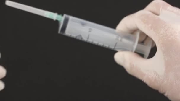 医療用手袋を手に取り使い捨て注射器をテスト針からキャップを外し黒の背景 — ストック動画