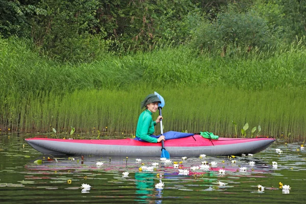 Girl on kayak among water lilies — Stok fotoğraf