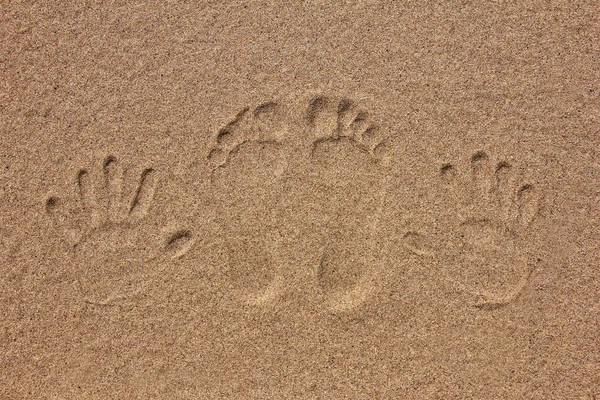 imprint of feet and hand on the sand