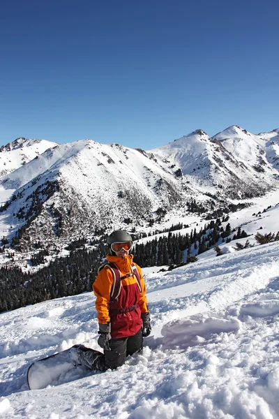 Chica snowboarder de pie sobre sus rodillas en la pendiente — Foto de Stock